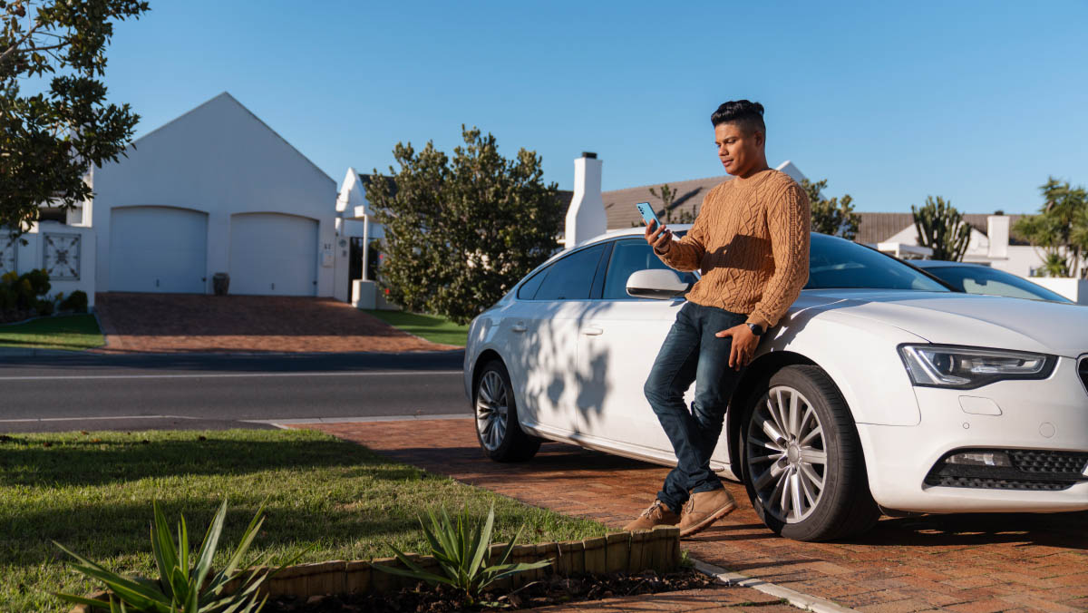 a person leaning on a parked car looking at a phone