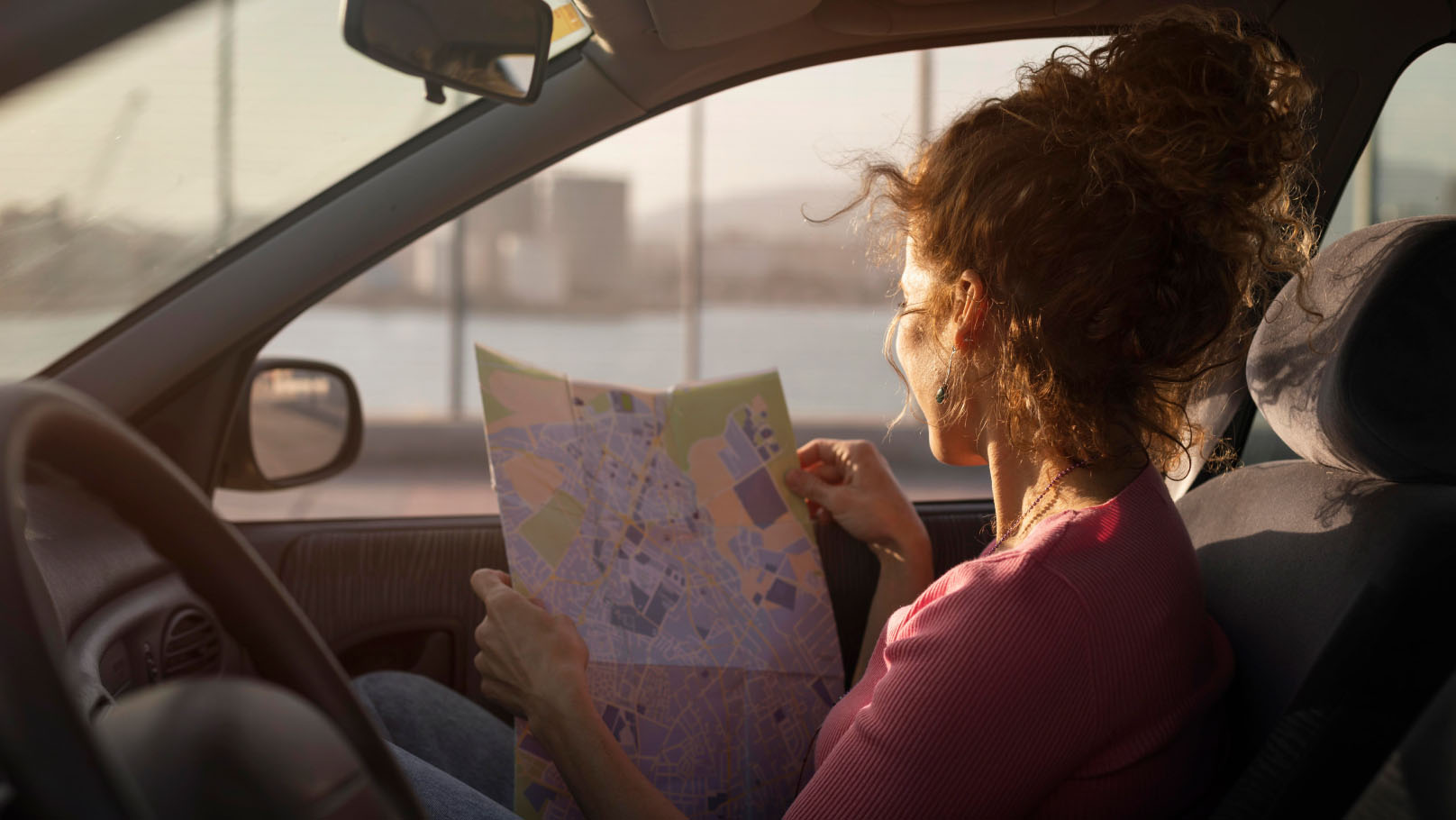 A person in the passenger seat of a car looking at a paper map