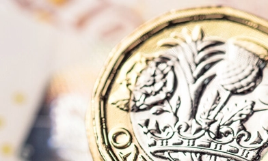 A £5 bank note placed on the left, a British one pound coin, face up on the right