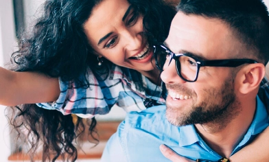 Young couple in kitchen both smiling while woman holds dangling key out in front of man
