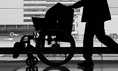Person pushing wheelchair along passage in airport