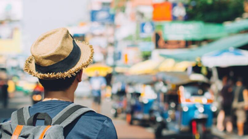 Male wearing hat and backpack looking in to distance ahead of him