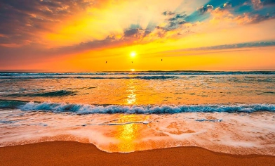 Beach with sea waves lapping on to beach and a beautiful sunset in the distance